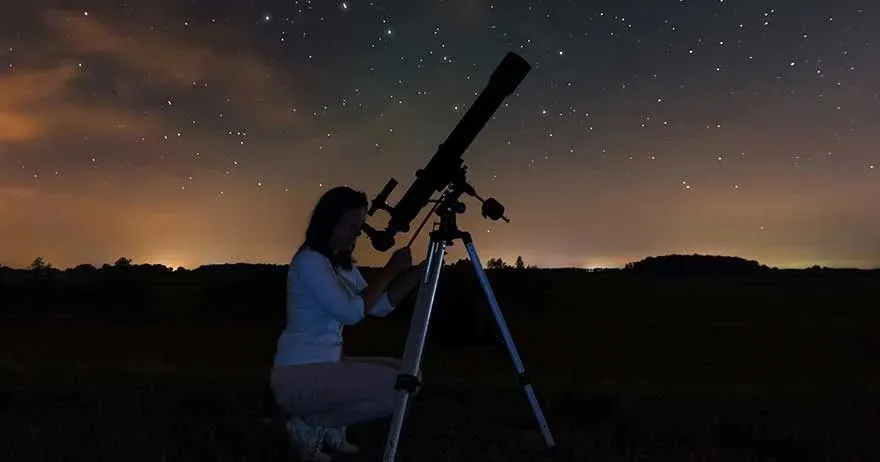 a girl star gazing through a telescope.